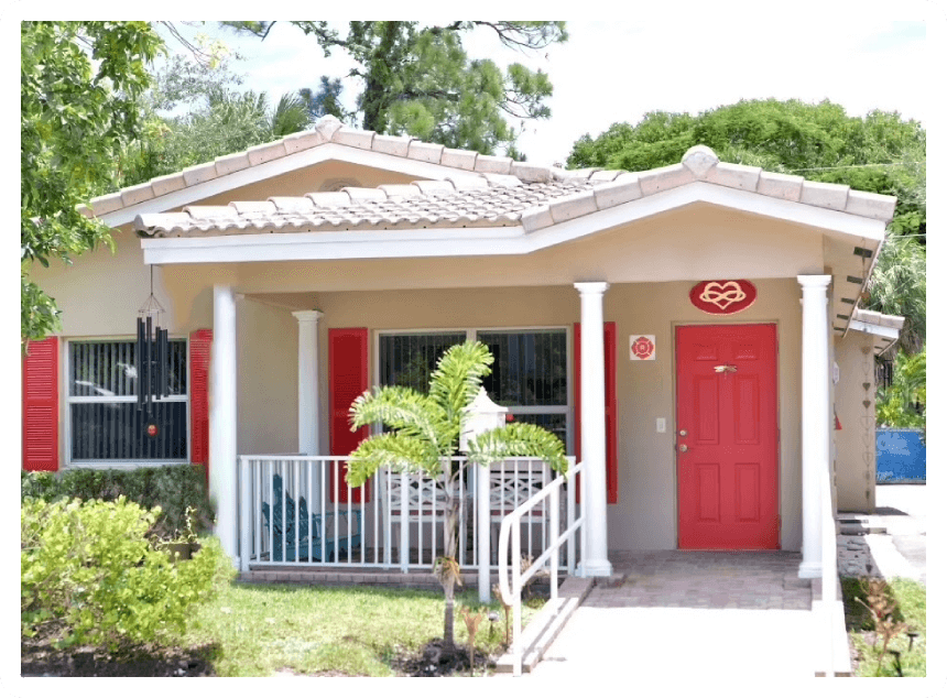 A red door and white porch in front of a house.