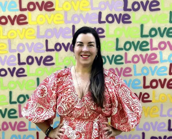 A woman standing in front of a wall with the word love written on it.